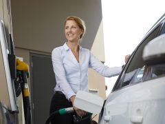 Een vrouw die haar auto volgooit bij het goedkope tankstation.