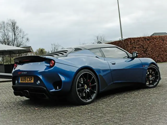 Een blauwe Lotus Evora GT410 Sport geparkeerd op een parkeerplaats.