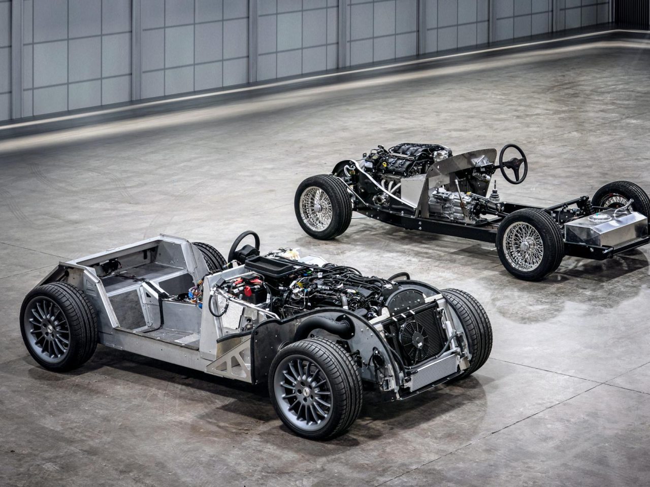 Twee zilveren Morgan-raceauto's staan geparkeerd in een kamer.