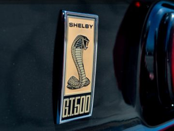 Een Mustang-badge op een zwarte auto met het woord Shelby erop.