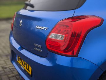 De achterkant van een blauwe Suzuki Swift.