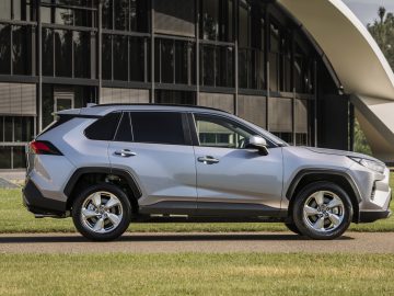 Het Toyota RAV4-busje uit 2019 staat geparkeerd voor een gebouw.
