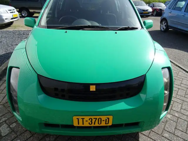 Een groene Toyota Will Cypha geparkeerd op een parkeerplaats.