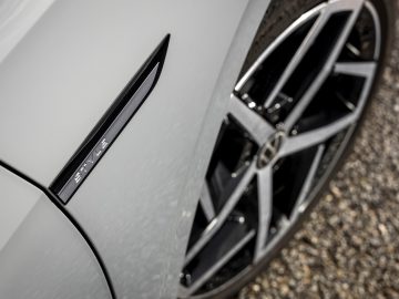 Een close-up van een zilveren Volkswagen Golf 8 met een logo op de zijkant.
