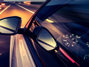 Een auto die 's nachts op een snelweg rijdt met een snelheid van 100.