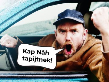 Een man in een auto die verkeersergernissen 2019 uitdrukt met een tekstballon die kap nah taipjin zegt.