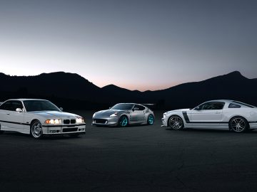 Drie sportwagens naast elkaar geparkeerd in de schemering, wat doet denken aan een scène uit The Fast and the Furious.