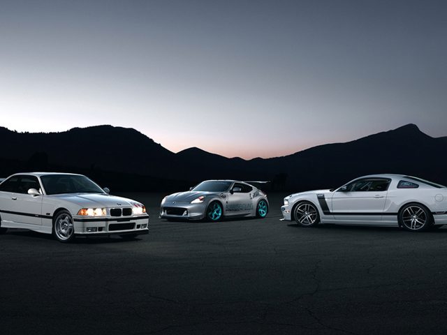 Drie sportwagens naast elkaar geparkeerd in de schemering, wat doet denken aan een scène uit The Fast and the Furious.