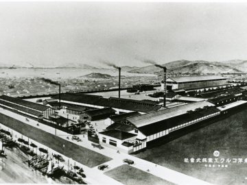 Historische zwart-witfoto van een Mazda-industrieel complex met schoorstenen, begin 20e eeuw.