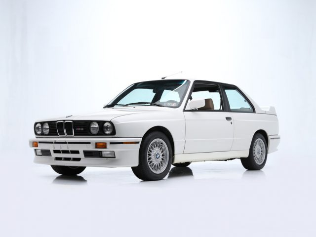 Witte vintage BMW-auto op een strakke, heldere achtergrond, die doet denken aan "The Fast and the Furious".