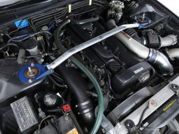 Een close-up van de motorruimte van een auto, met verschillende componenten en aanpassingen geïnspireerd door The Fast and the Furious.