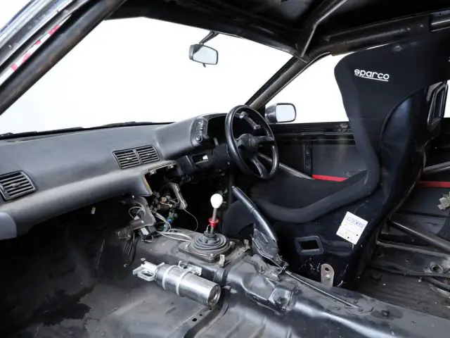 Interieur van een uitgeklede raceauto, die doet denken aan The Fast and the Furious, met Sparco racestoel en rolkooi.