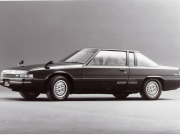 Vintage Mazda coupé-auto met turbo-branding op een effen achtergrond.