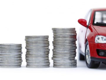 Een rode auto met daarnaast stapels munten, die de gemiddelde aanschafprijs vertegenwoordigen.