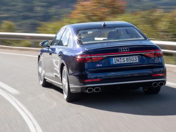 Een blauwe Audi S8 sedan rijdt op een gebogen weg met bewegingsonscherpte op de achtergrond.
