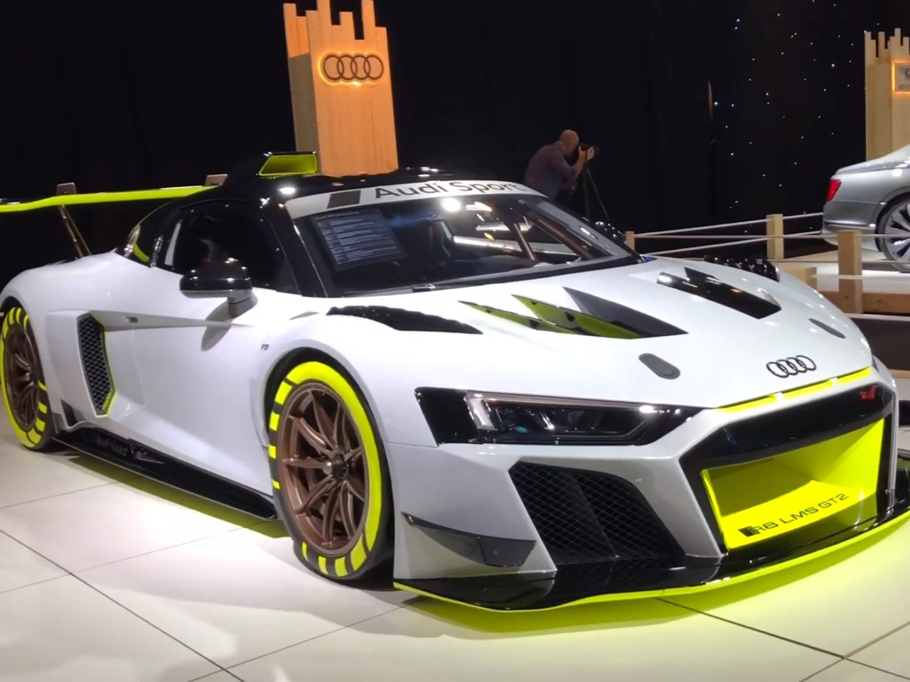 Audi R8 LMS GT3-raceauto te zien op het Autosalon van Brussel 2020 met een toeschouwer op de achtergrond.