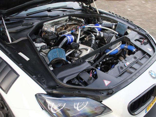 Een BMW M6 GT3-auto met open motorkap, waardoor een gedetailleerd zicht op de gewijzigde motorruimte zichtbaar is.