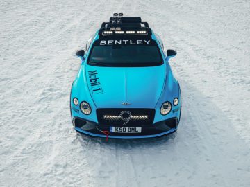 Een blauwe Bentley Continental Ice GT uitgerust met extra verlichting op besneeuwd terrein.