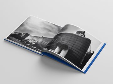 Een opengeslagen fotoboek met een zwart-witafbeelding van de laatste Bugatti-raceauto's.