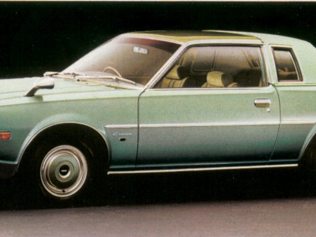 Uitstekende groene Mazda-coupéauto met dubbele zijspiegels en gele koplampkappen.