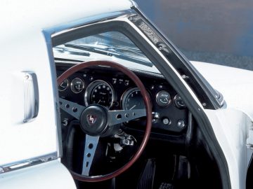 Binnenaanzicht van een klassieke Mazda-auto met het stuur en het dashboard met analoge meters.