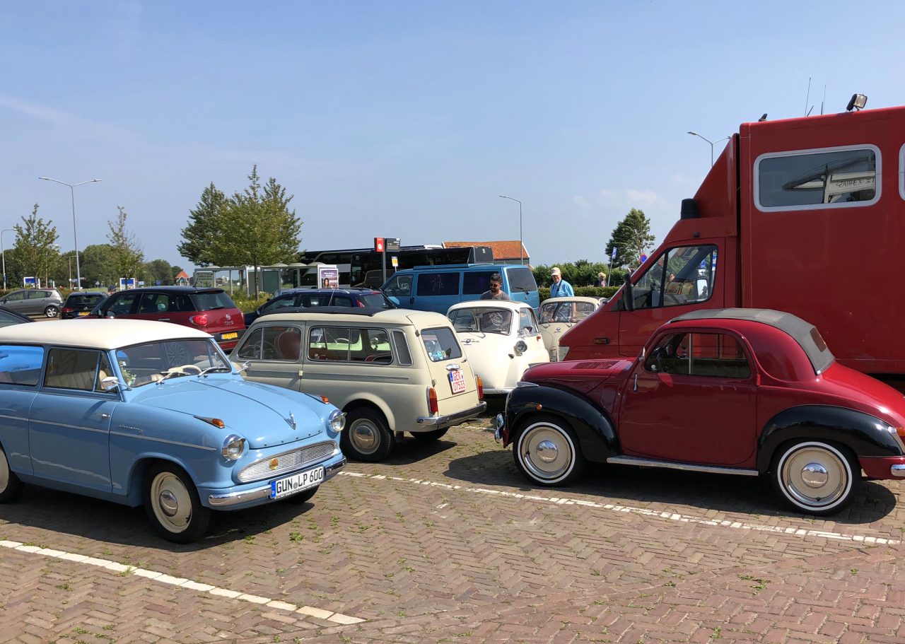 Vintage, moderne auto's en een dwergauto die op een zonnige dag veel geparkeerd staat.