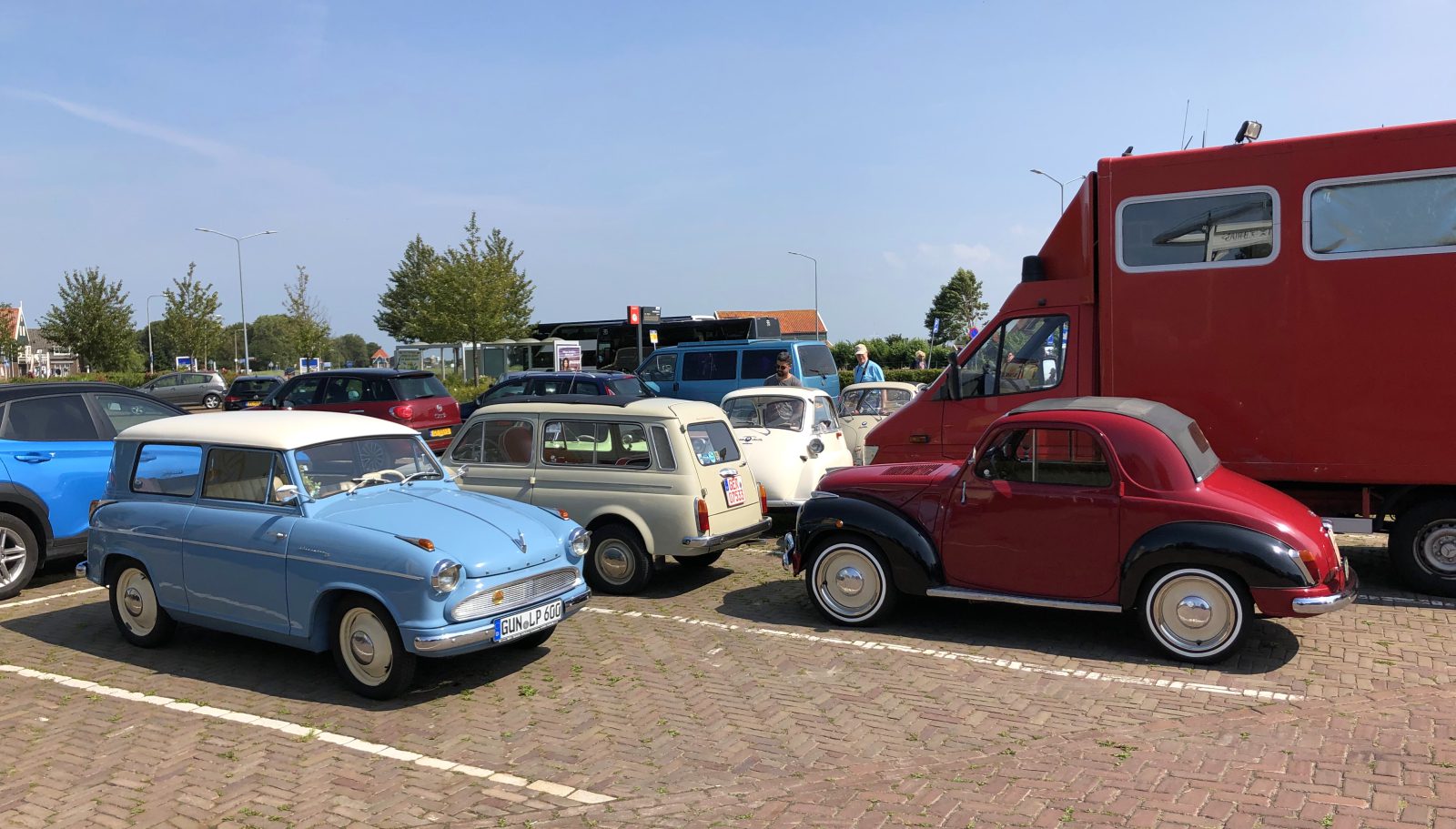 Vintage, moderne auto's en een dwergauto die op een zonnige dag veel geparkeerd staat.
