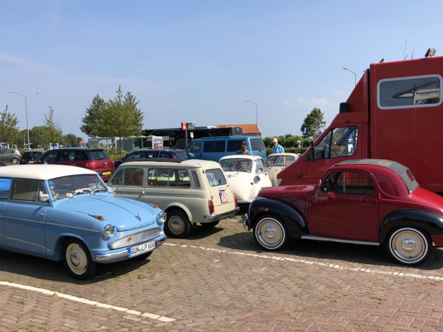 Vintage, moderne auto's en een dwergauto die op een zonnige dag veel geparkeerd staat.