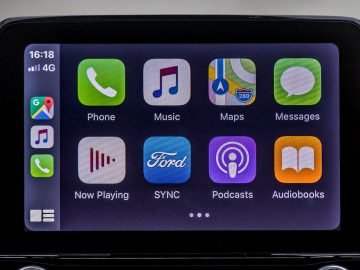 Smartphone-interface weergegeven op het infotainmentscherm van een Ford Puma met verschillende app-pictogrammen voor telefoonfuncties, muziek, kaarten, berichten en andere mediatoepassingen.