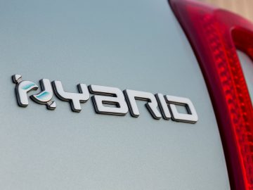 Close-up van een 'Fiat 500 Hybrid'-badge op de buitenkant van een voertuig.