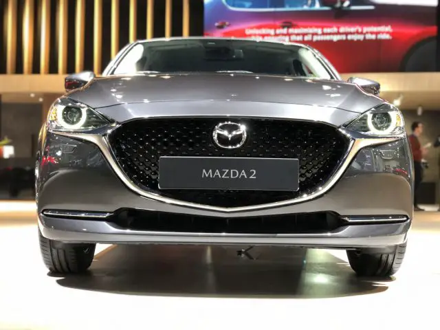 Een Mazda2-auto tentoongesteld op het Autosalon van Brussel 2020 met de nadruk op de grille en het embleem.