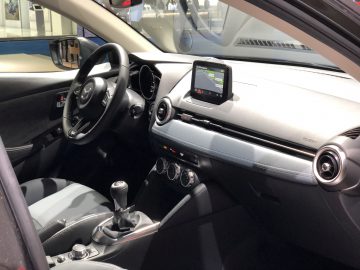 Binnenaanzicht van een moderne auto tentoongesteld op het Autosalon van Brussel 2020, met het stuur, het dashboard, het infotainmentscherm en de versnellingspook met handgeschakelde versnellingsbak.