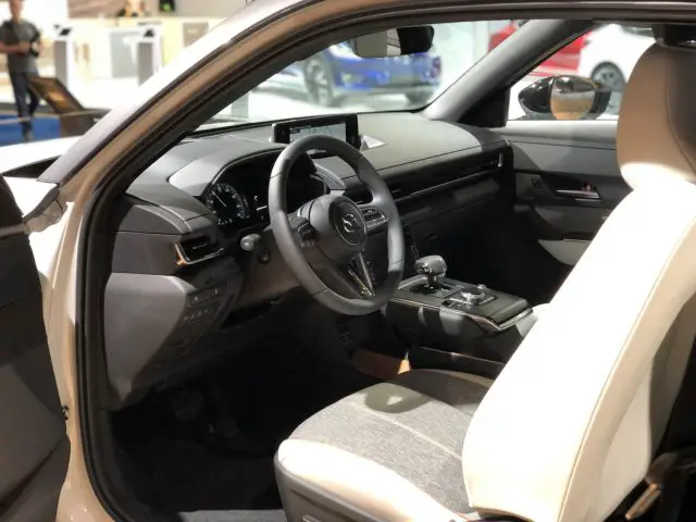 Binnenaanzicht van een moderne auto op het Autosalon van Brussel 2020 met het bestuurdersportier open, met het stuur, het dashboard en de middenconsole.