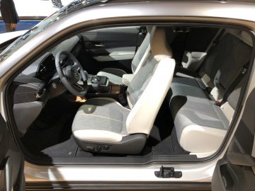 Binnenaanzicht van een moderne auto op het Autosalon van Brussel 2020 met de bestuurdersstoel, de passagiersstoel en een deel van het achterste zitgedeelte met de deur open.