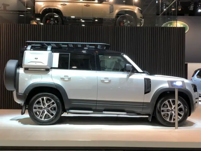 Een moderne witte SUV tentoongesteld op het Autosalon van Brussel 2020 met een imperiaal en een aan de achterkant gemonteerde opbergdoos.