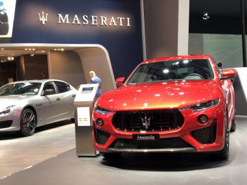 Rode Maserati Levante te zien op het Autosalon van Brussel 2020 met het Maserati-logo en merk op de achtergrond.