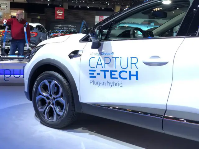 Witte Renault Captur plug-in hybride te zien op het Autosalon van Brussel 2020 met een bezoeker op de achtergrond.