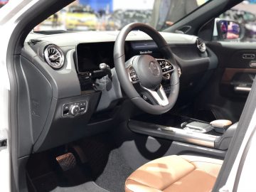 Binnenaanzicht van een moderne auto tentoongesteld op het Autosalon van Brussel 2020, met het dashboard, het stuur en de bruinleren stoelen.