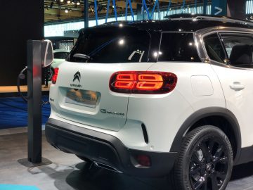 Witte Citroën C5 Aircross SUV tentoongesteld op het Autosalon van Brussel 2020, aangesloten op een laadstation voor elektrische voertuigen.