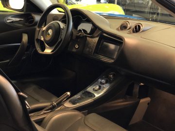 Binnenaanzicht van een luxe Lotus-auto met leren stoelen, een middenconsole met meerdere bedieningselementen en een stuur met een Hein Noortman-logo.