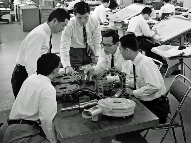 Ingenieurs werken samen aan de mechanische componenten van Mazda in een kantooromgeving.