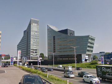 Moderne kantoorgebouwen met uitgesproken architectonische ontwerpen op een zonnige dag, met een prominente Honda-showroom.