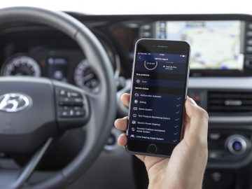 Een persoon die een smartphone vasthoudt met een open voertuigdiagnose-app in een Hyundai i10-auto.