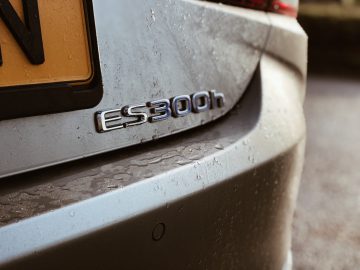 Close-up van een stoffige Lexus ES 300h met het modelbadge "es300h" zichtbaar op de achterkant.