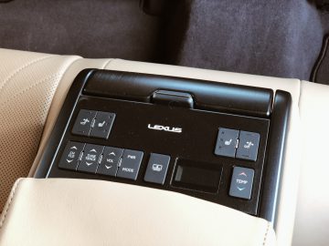 Bedieningspaneel op een Lexus ES 300h auto-armsteun met diverse knoppen voor stoelverstelling, audio en klimaatregeling.
