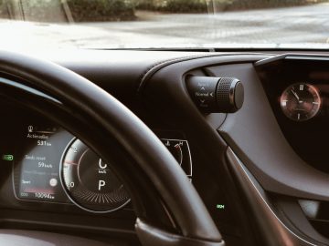 Voertuigdashboard van de Lexus ES 300h met snelheidsmeter, versnellingspositie en keuzeknop voor de rijmodus met de opties "sport", "normaal" en "eco".