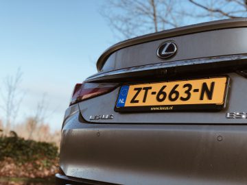 Een close-up van de achterkant van een grijze Lexus ES 300h-auto met Nederlands kenteken, buiten geparkeerd.