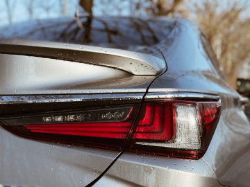 Close-up van het achterlicht en de spoiler van een natte Lexus ES 300h met druppels op het oppervlak.