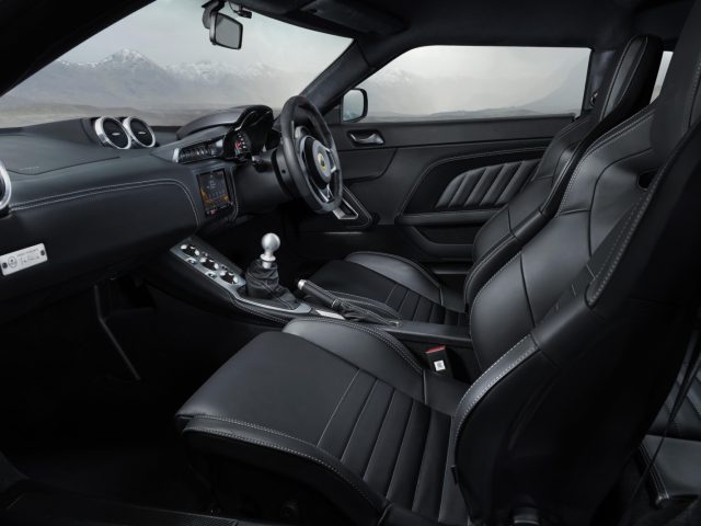 Binnenaanzicht van de Lotus Evora GT410, met zwart lederen stoelen, handgeschakelde versnellingsbak en een digitale dashboardconsole.