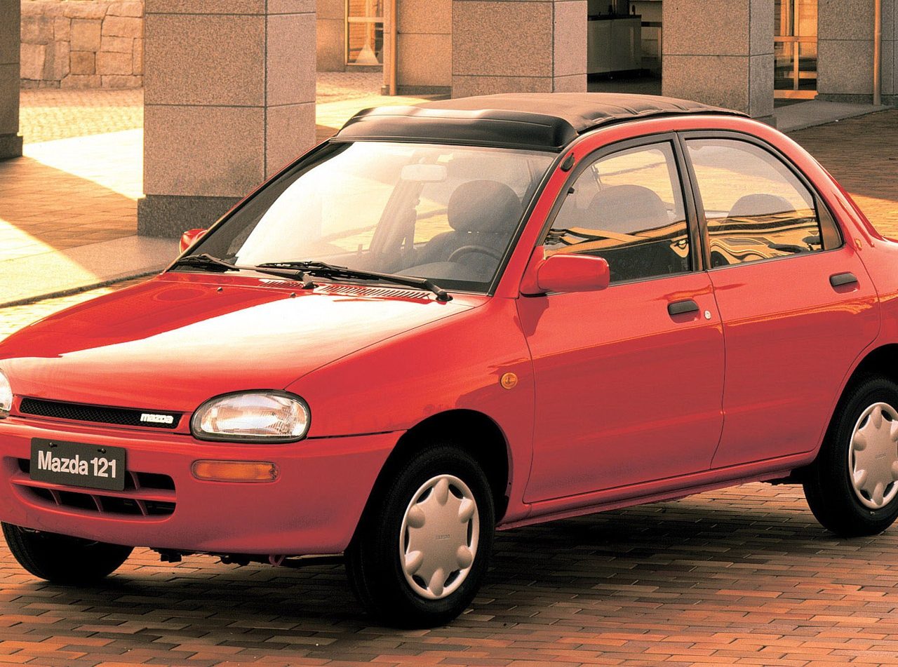 Rode Mazda 121 geparkeerd in een stedelijke omgeving.